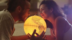 Junges verliebtes Paar hält leuchtenden Globus fest
